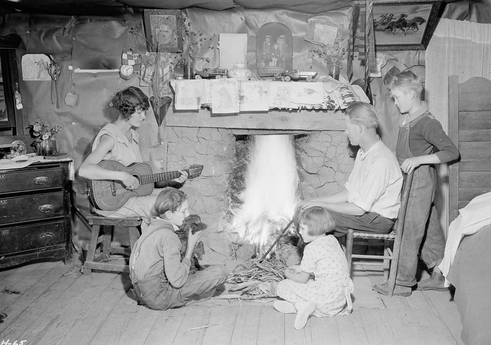 A family huddle around a fire for warmth – music and drawing are cheap ways to keep everyone distracted from the cold