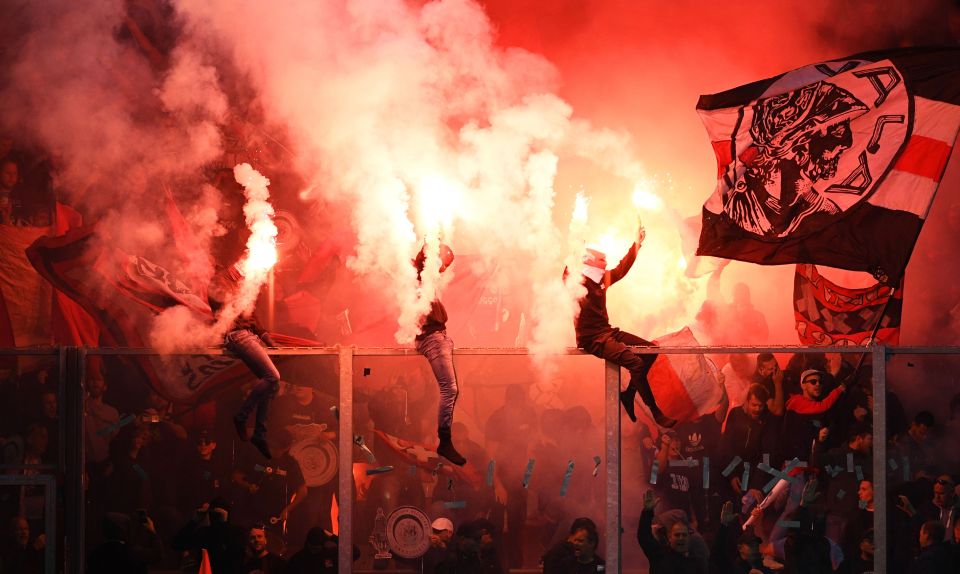  Masked Ajax fans let flares off inside of the De Vijverberg