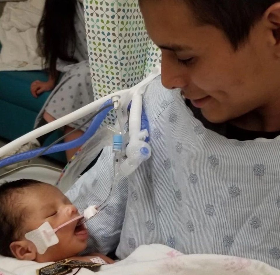 Distraught dad Yovani Lopez cradles his son as the newborn fights for life in hospital after being cut from his murdered mum’s womb