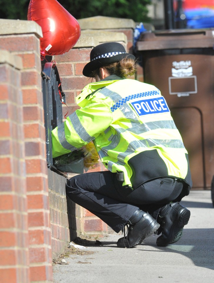  A police officer puts some flowers down at the scene of the killings