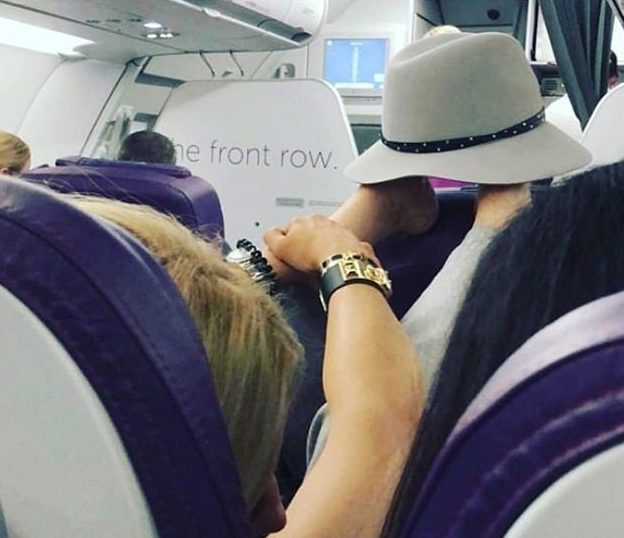  A grim photo captures a woman resting her bare feet on top of the chair in front of her during a flight