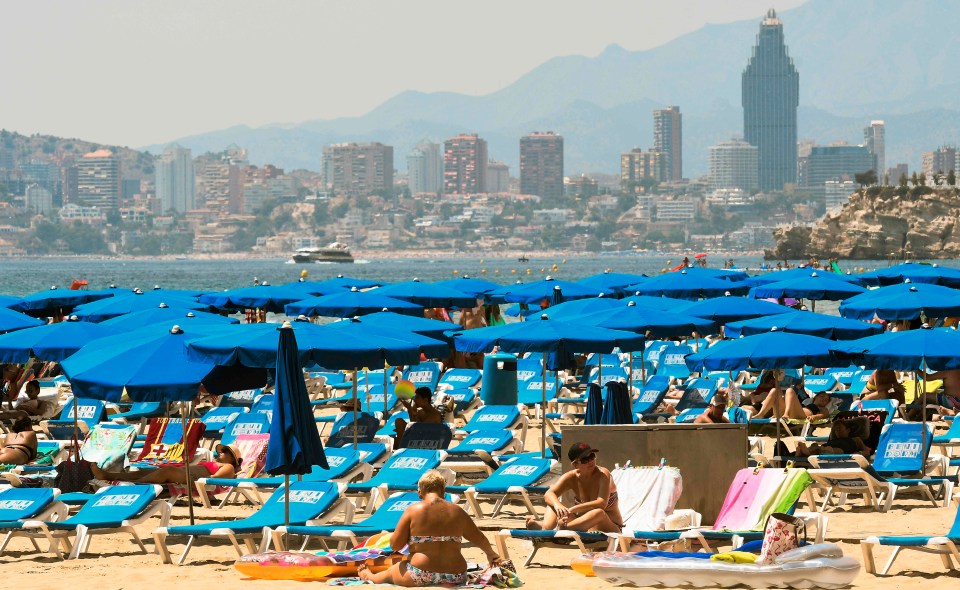 Beach-goers cool off and sunbathe on the beach of the seaside resort of Benidorm