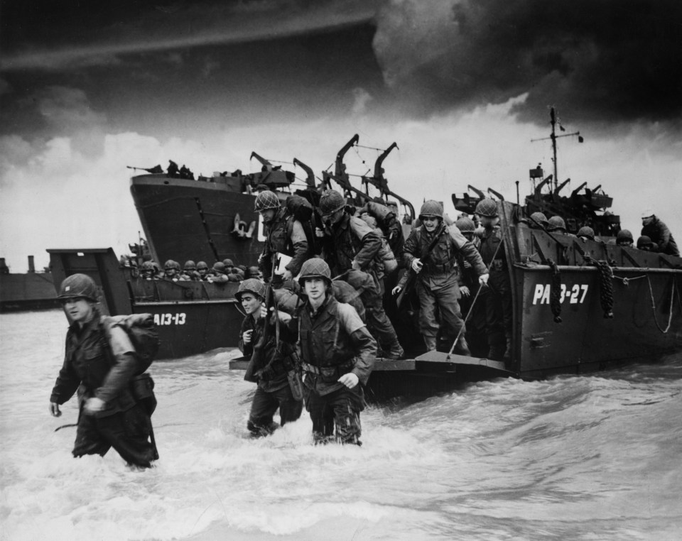  Allied troops disembarking landing craft on the beach of Normandy on June 6, 1944