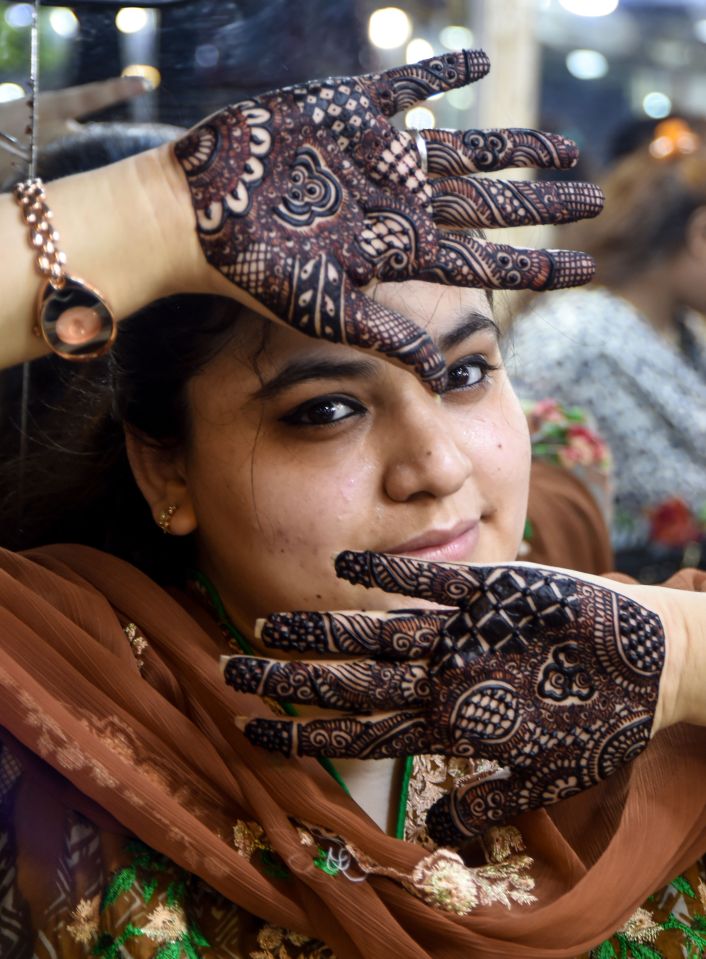 A Pakistani customer shows her decorated hands with henna designs at a beauty salon ahead of the Eid al-Fitr holiday, in Karachi 