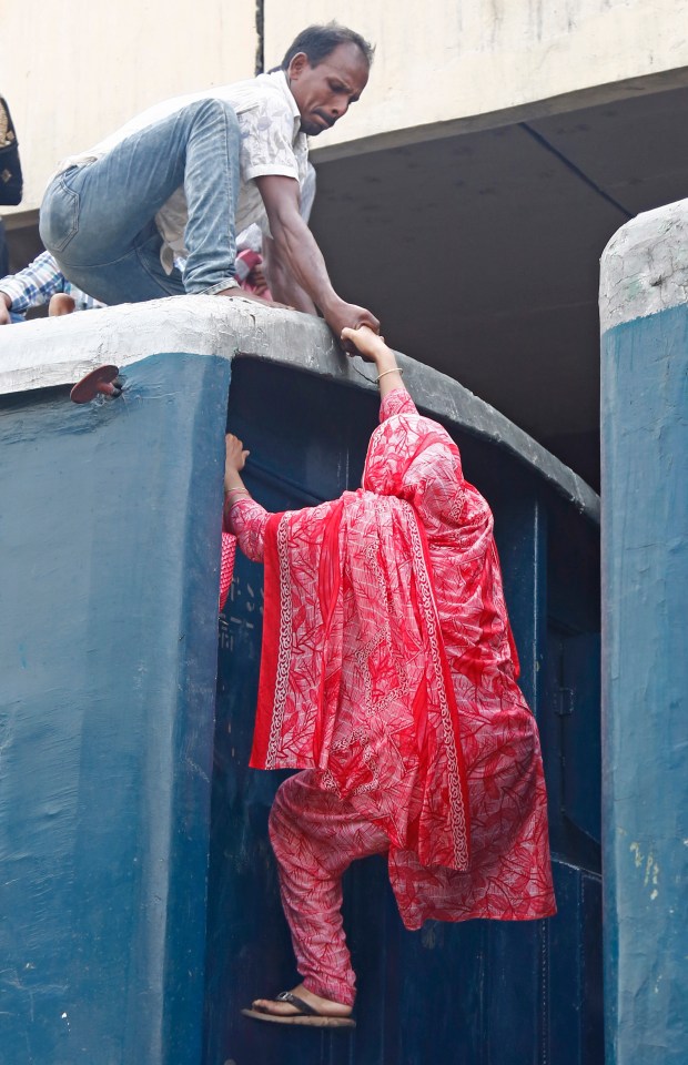 One woman is given a helping hand as she climbs up onto a train in Bangladesh