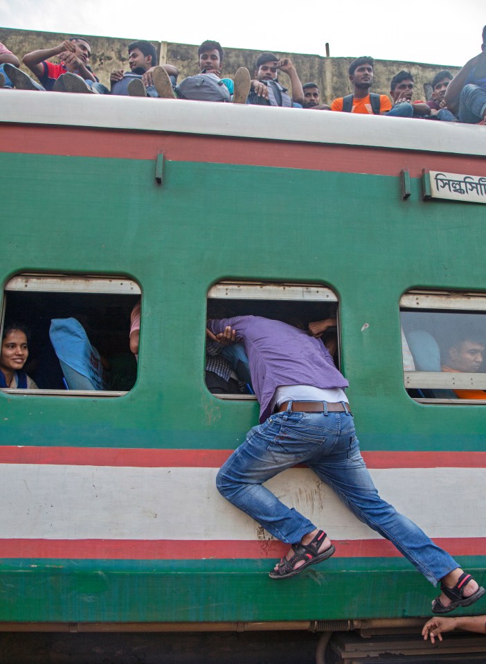 One Bangladeshi climbs through the window of a packed train as it pulls away from the platform