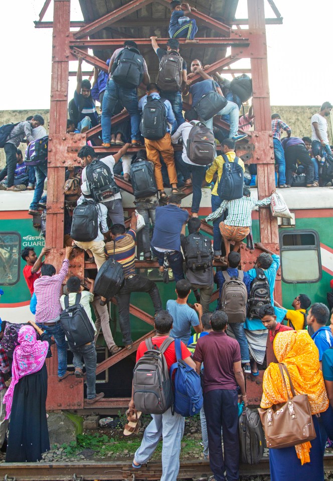 Passengers climbs up the side of a bridge to grab a spot on the roof of a train