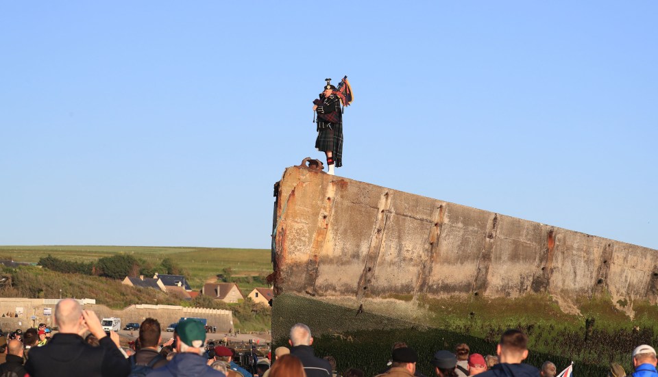 A lone piper plays on the Mulberry harbour at Arromanches in Normandy, in northern France, as British Army personnel mark the exact moment the first British soldier landed on Gold Beach 75 years ago