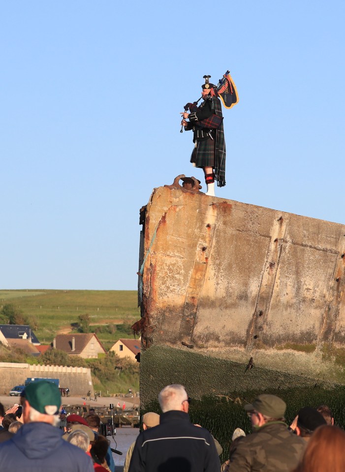 A lone piper plays on the Mulberry harbour at Arromanches in Normandy, in northern France, to mark the 75th anniversary of D-Day