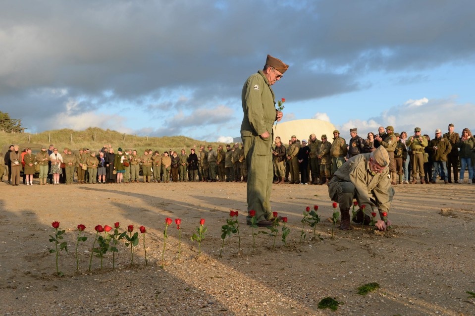 French WWII enthusiasts from the group Overlord 76 plant red roses in the sand in tribute to Americans who died on Utah beach in Sainte-Marie-du-Mont