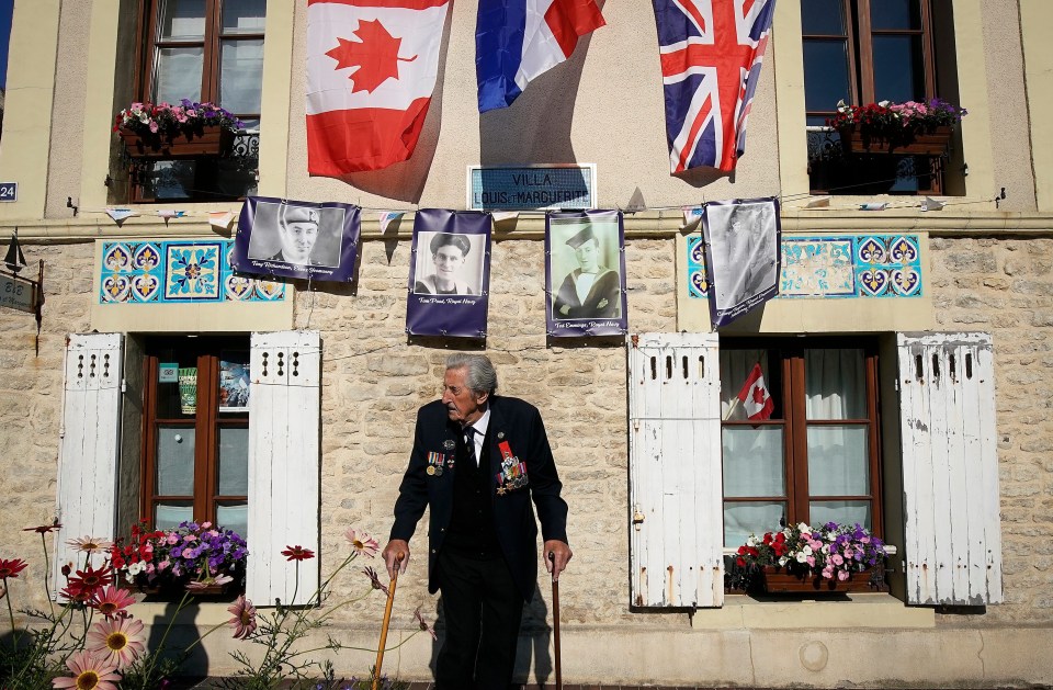 D-Day landing craft veteran, Ted Emmings, aged 94, of The Royal Navy, walks past a villa in Arromanche that has been decorated and is adorned with a photograph of him and other veterans