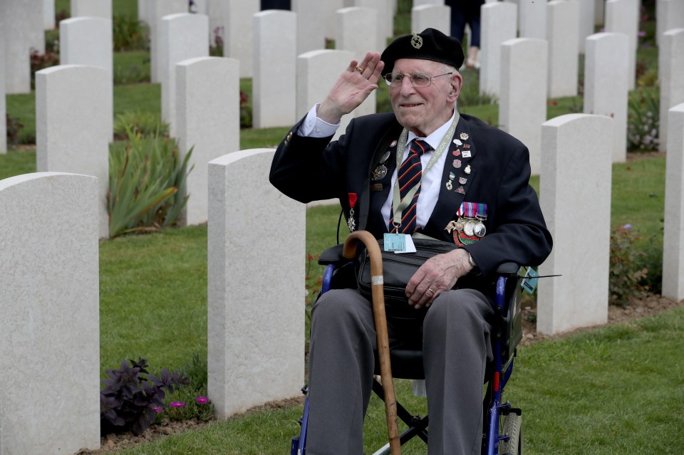 A veteran gives a salute amongst the headstones at the Commonwealth War Graves Commission Cemetery in Bayeux