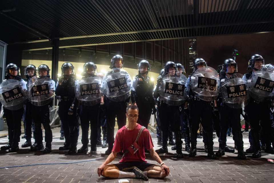  A protester sits meditating in front of a row of riot police