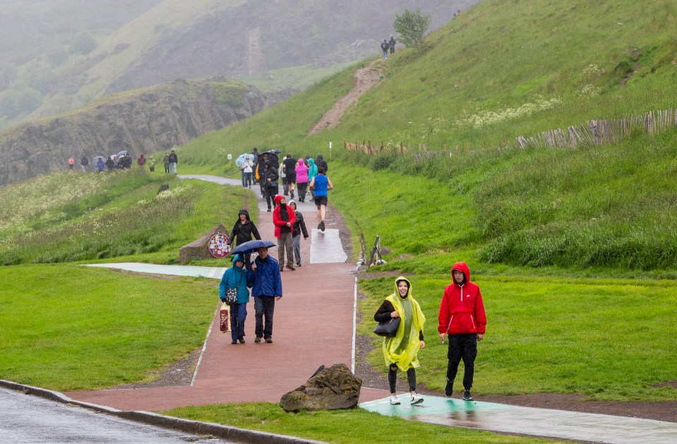 Tourists in Holyrood Park, Edinburgh battle heavy rain as bad weather affects most of the country