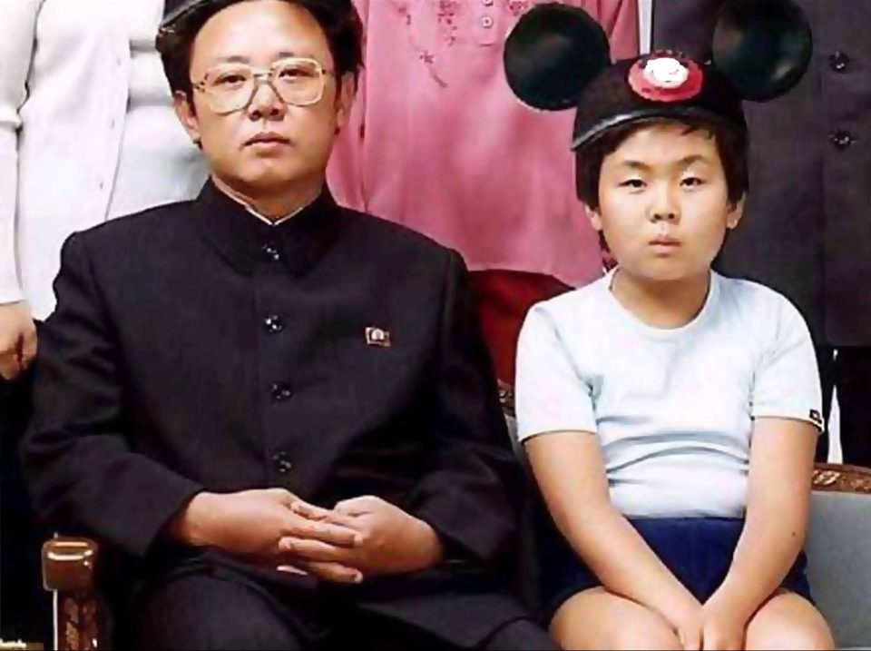  Kim Jong-un, right, as a small child wearing a Mickey Mouse hat while sitting next to his father Kim Jong-il