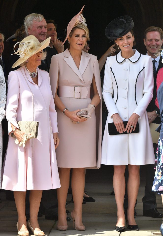  Kate holds onto a black clutch as she wears a matching fascinator and heels