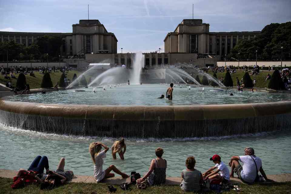  Youngsters sunbathe and cool themselves down in a pond at the Trocadero esplanade in Paris