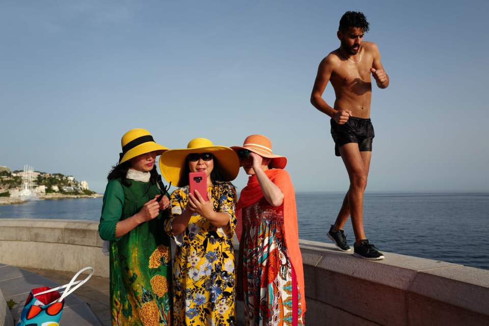  A man walks by as tourists take selfies on the French Riviera city of Nice