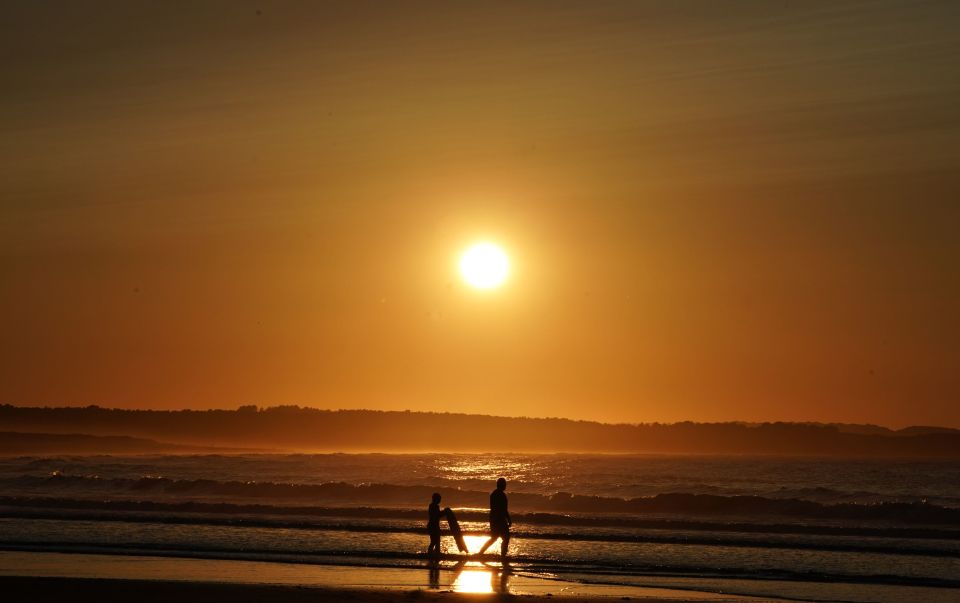  Two surfers walk on the beach on Belhaven beach near Dunbar at sunset