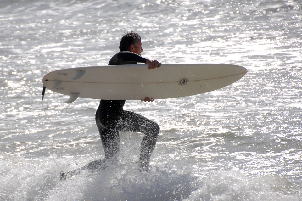  A surfer hits the waves this morning at Preston Beach in Weymouth