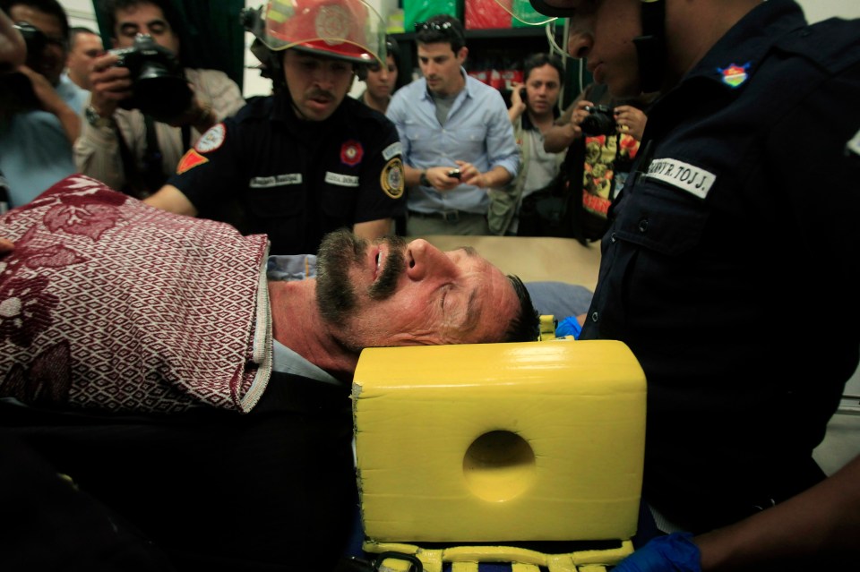 McAfee is seen lying in a stretcher after allegedly experiencing heart issues following his arrest in Guatemala