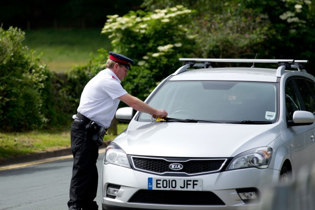 Traffic warden putting ticket on car