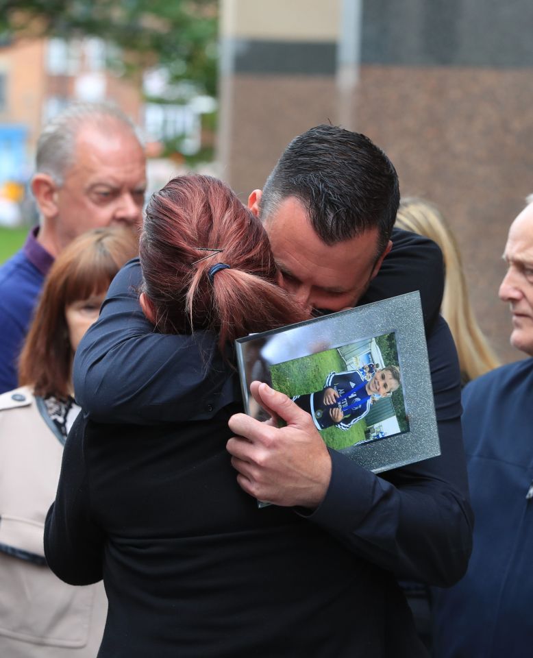  Andrew Metcalf hugs a supporter and clutches a photo of his son Stanley after the sentencing