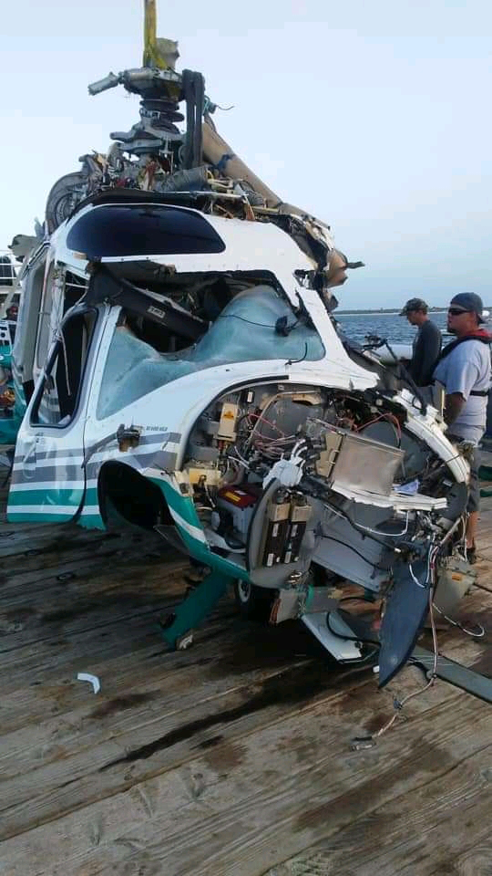  The ruined aircraft can be seen being craned onto a boat as investigators inspect the wreckage