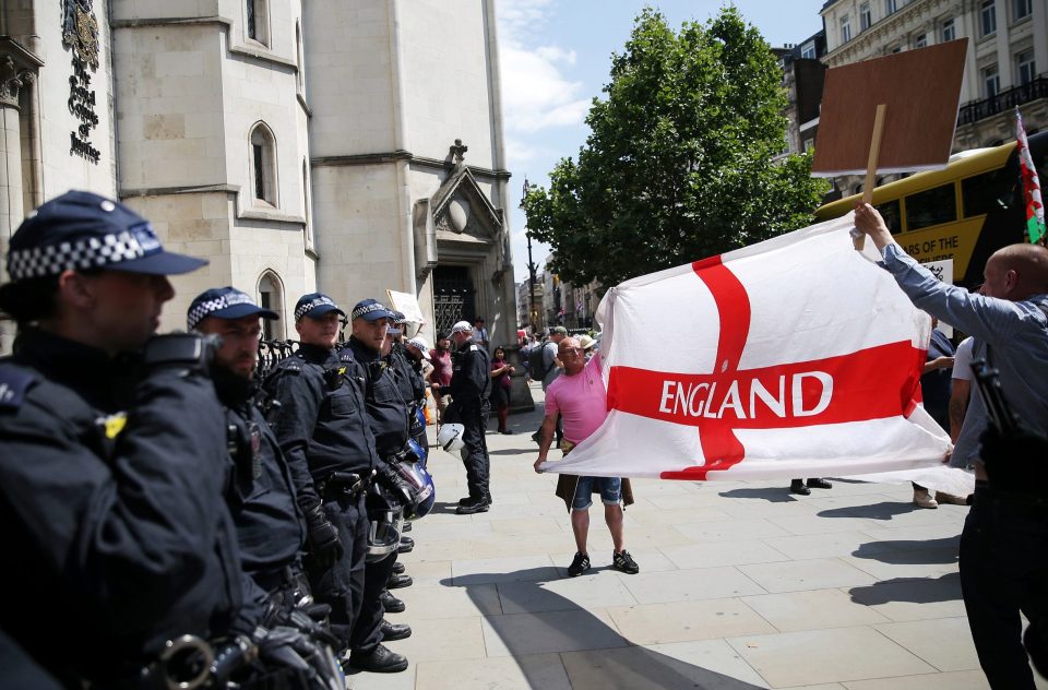  Robinson supporters hold up an England flag in front of police