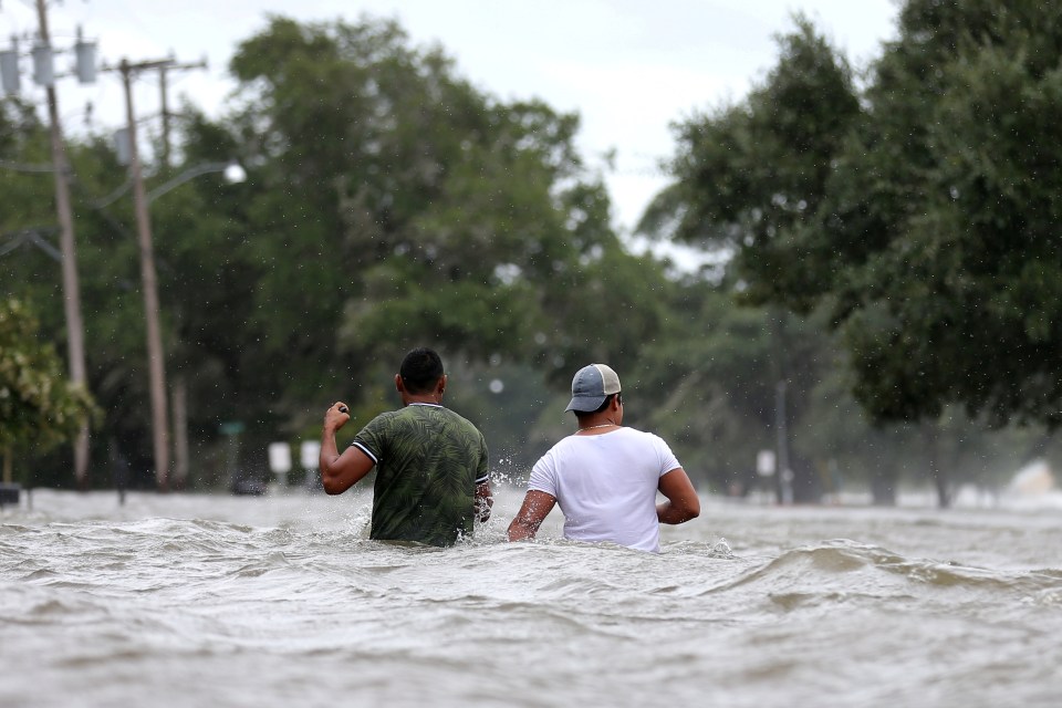 People wade through a flooded street after Storm Barry in Mandeville, Louisiana