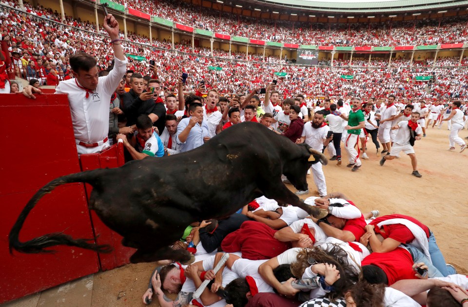  Revellers, dressed in the traditional white and red, jump out of a bull's path at the end of the 850 metre run