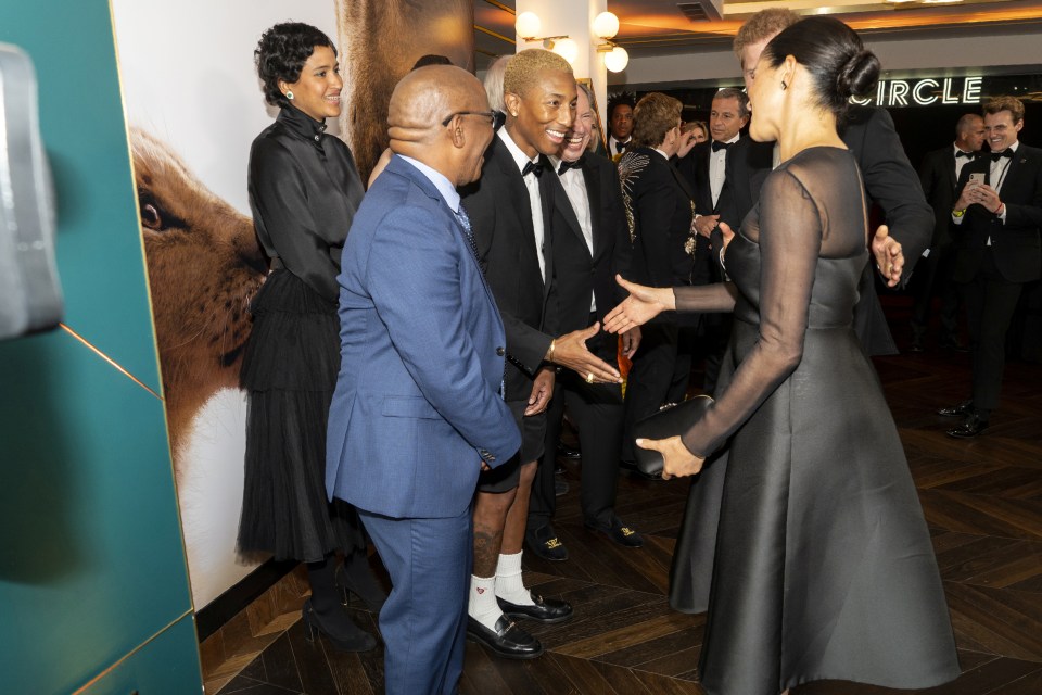  Meghan shakes hands with singer Pharrell Williams