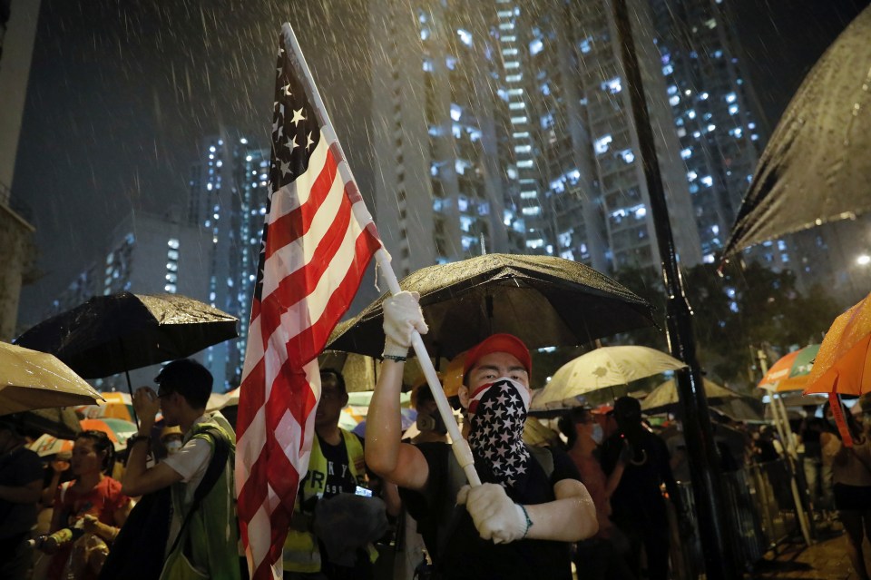  A protester waves an American flag as hundreds of protesters gather outside Kwai Chung police station in Hong Kong, Tuesday, July 30