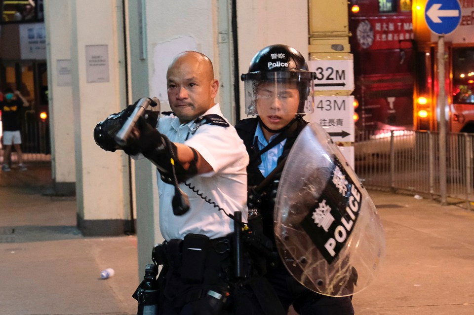  A cop points a gun towards anti-extradition bill campaigners who surrounded a police station where detained protesters were being held during clashes in Hong Kong, July 30