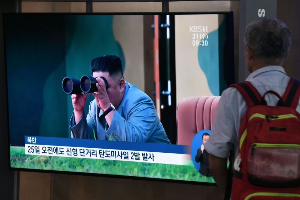  A passerby watches a broadcast showing North Korean leader Kim Jong-un watching a missile launch, as he walks through a railway station in Seoul