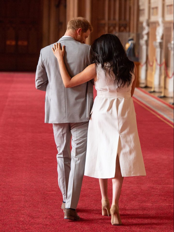  Meghan shows approval of Harry's fathering techniques by placing an arm around him as he carries Archie