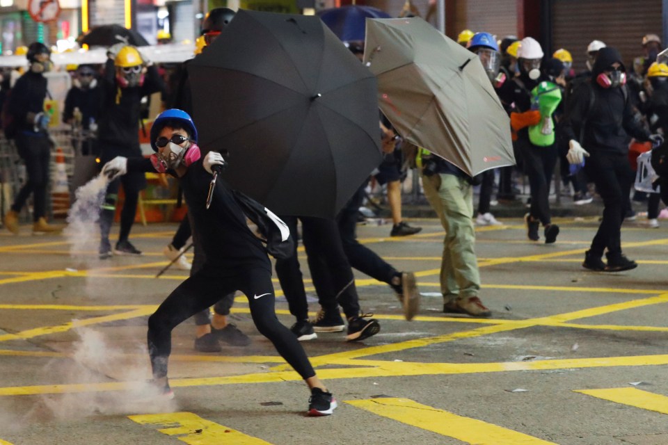  An anti-extradition bill protester throws back a tear gas canister at the police in Causeway Bay