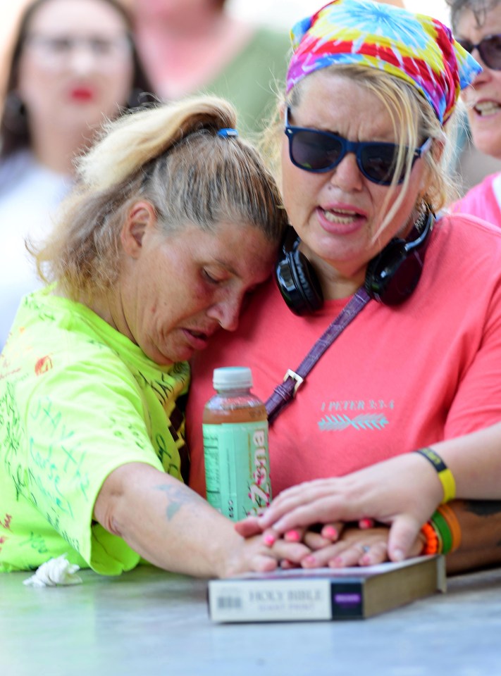  People embrace and hold the Holy Bible as crowds gather for a prayer vigil in downtown Dayton