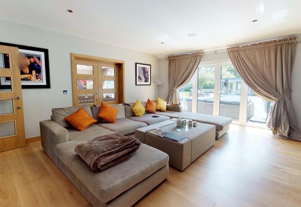  One sitting room boasts a large grey sofa with orange cushions while film posters adorn the walls, making it the perfect space to Netflix and chill