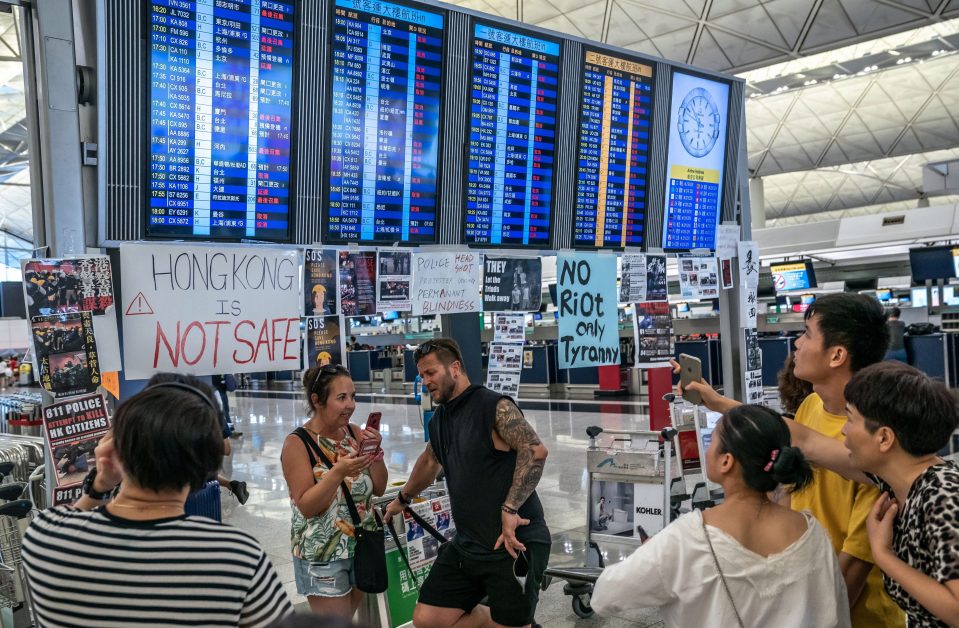  Tourists look at the information panel as it shows all flights are cancelled