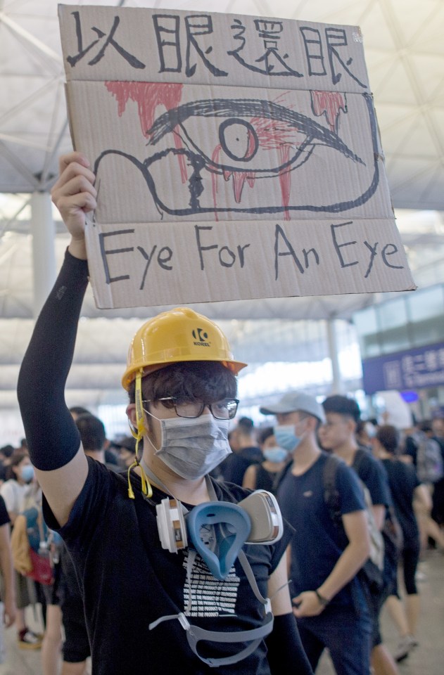  A protester holding up a banner reading 'Eye for an eye' joins demonstrators occupying the airport