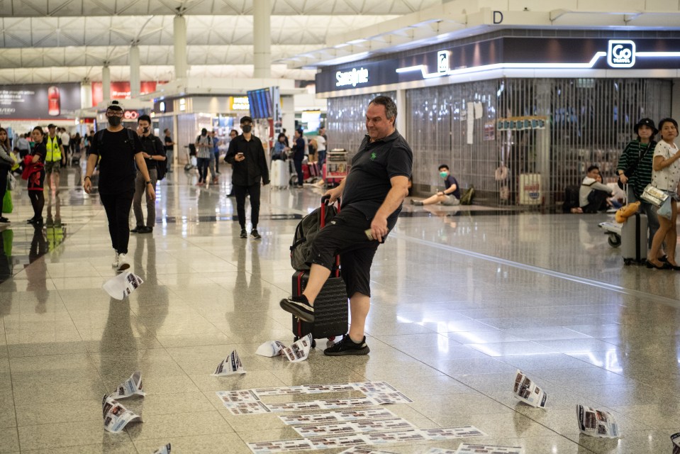  An angry passenger kicks flyers left behind by protesters at the airport