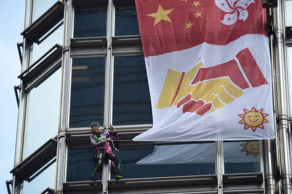  He hangs a fabric displaying Chinese and Hong Kong flags shaking hands