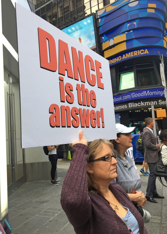  People rallied around the dancers in Time Square with signs