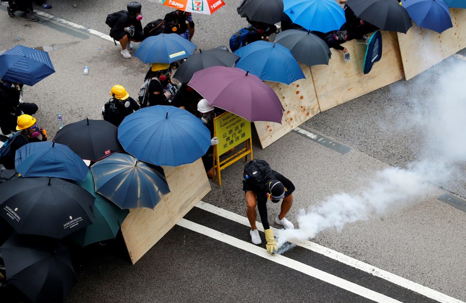  A protester picks up an exploded tear gas shell to throw back to policemen