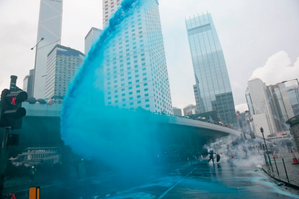  A stream of bright blue water is aimed across the city streets