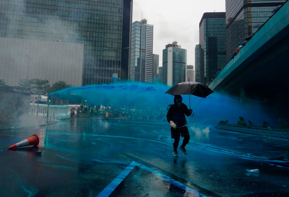  A protester runs for cover as police fire blue dye from water cannons