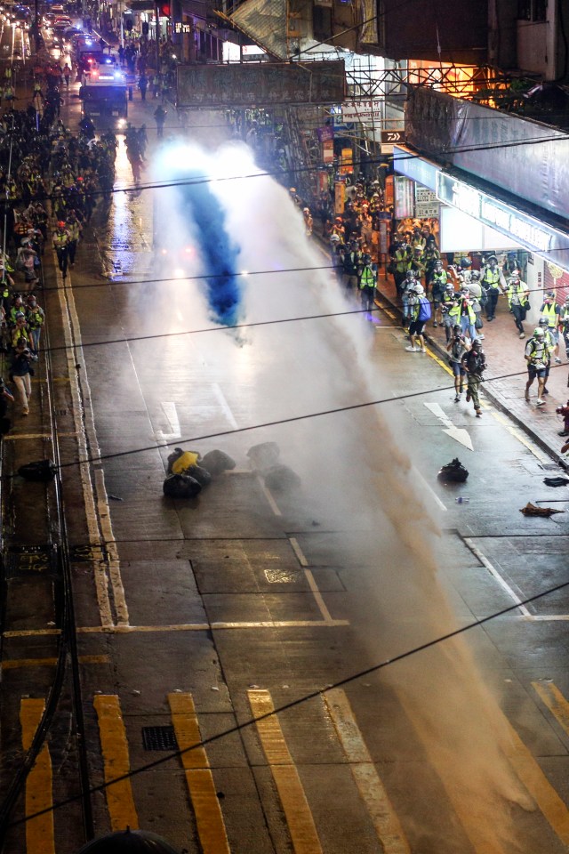  A police vehicle fires a water cannon down a road during the anti-government rally