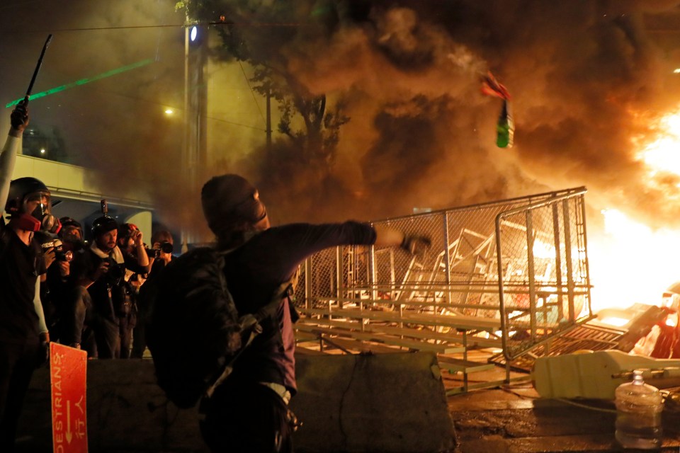  A protester throws a petrol bomb toward a barrier