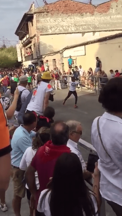  One man runs down the middle of the road just metres away from the charging bull